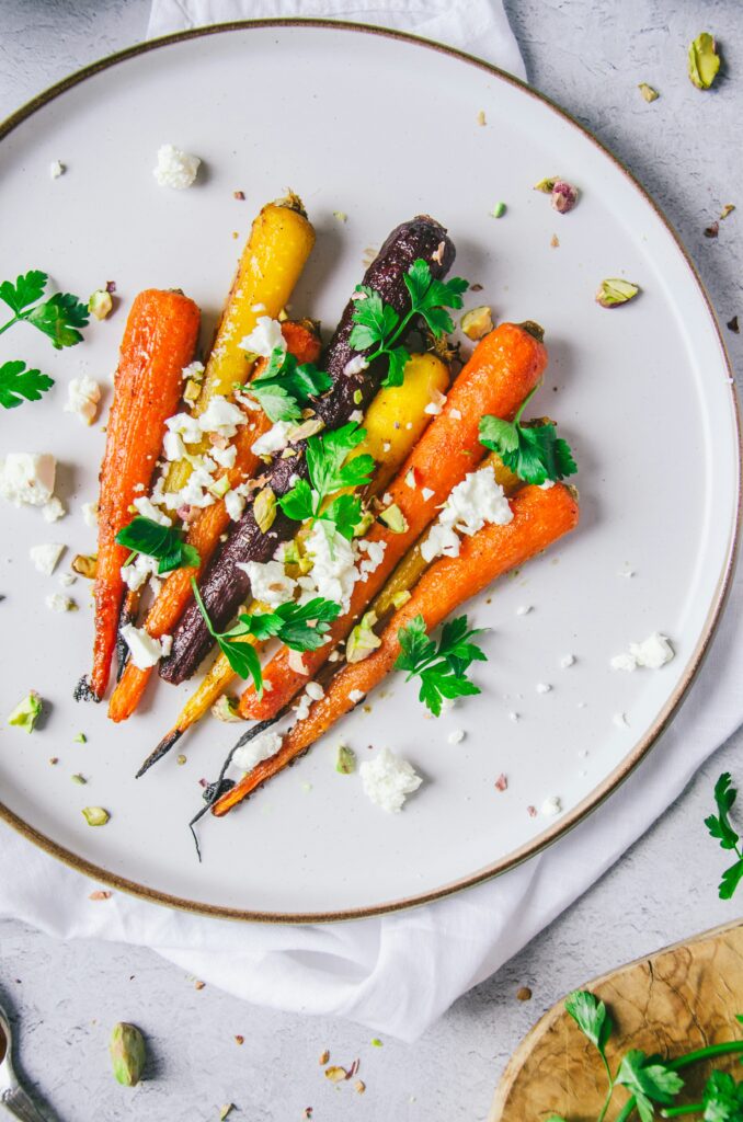 different colored roasted carrots with toppings sprinkled on top